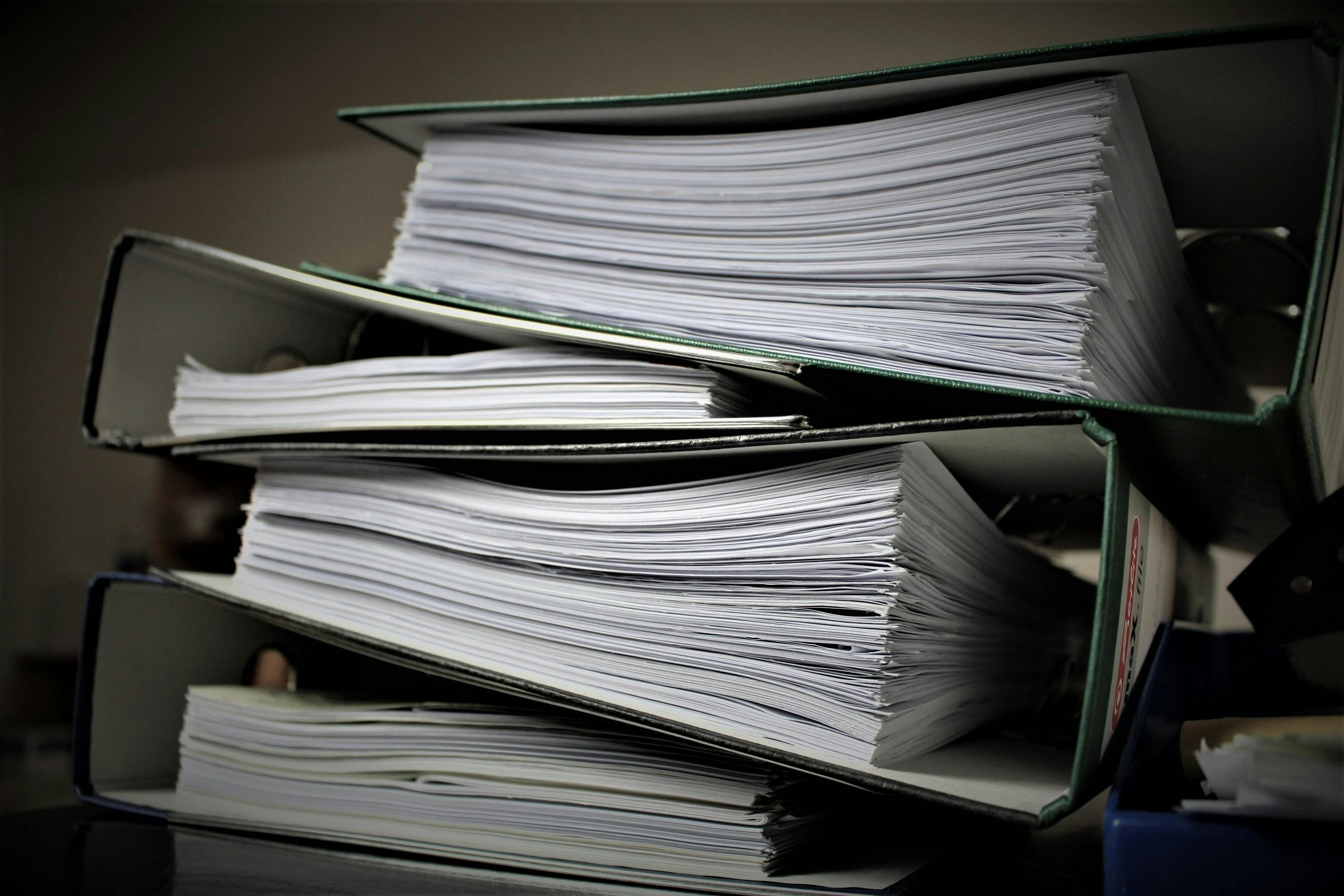 A stack of ring binders with pages of paper inside them