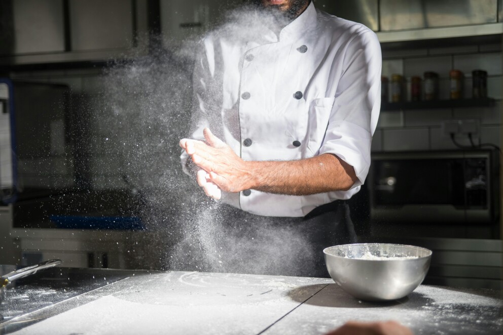 Baker clapping hands in cloud of flour dust 