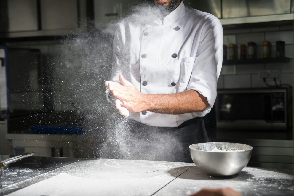 Baker clapping hands in cloud of flour dust 