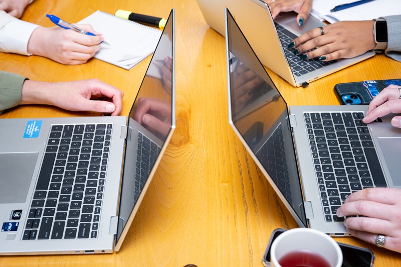 Close up of three laptops on a desk.